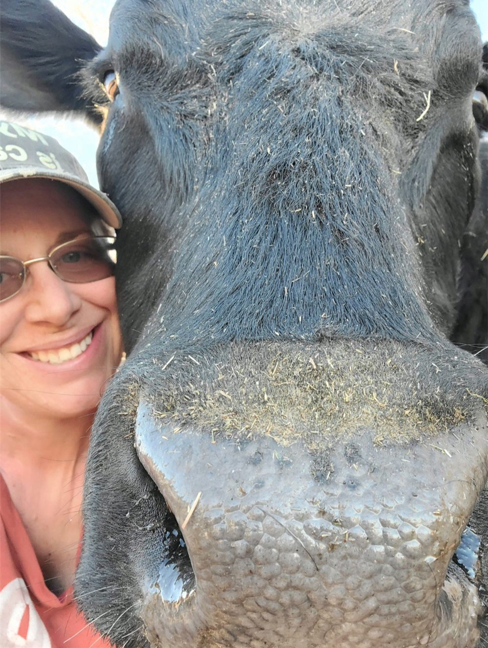 Allison smiling, cheek pressed against the face of a large black cow
